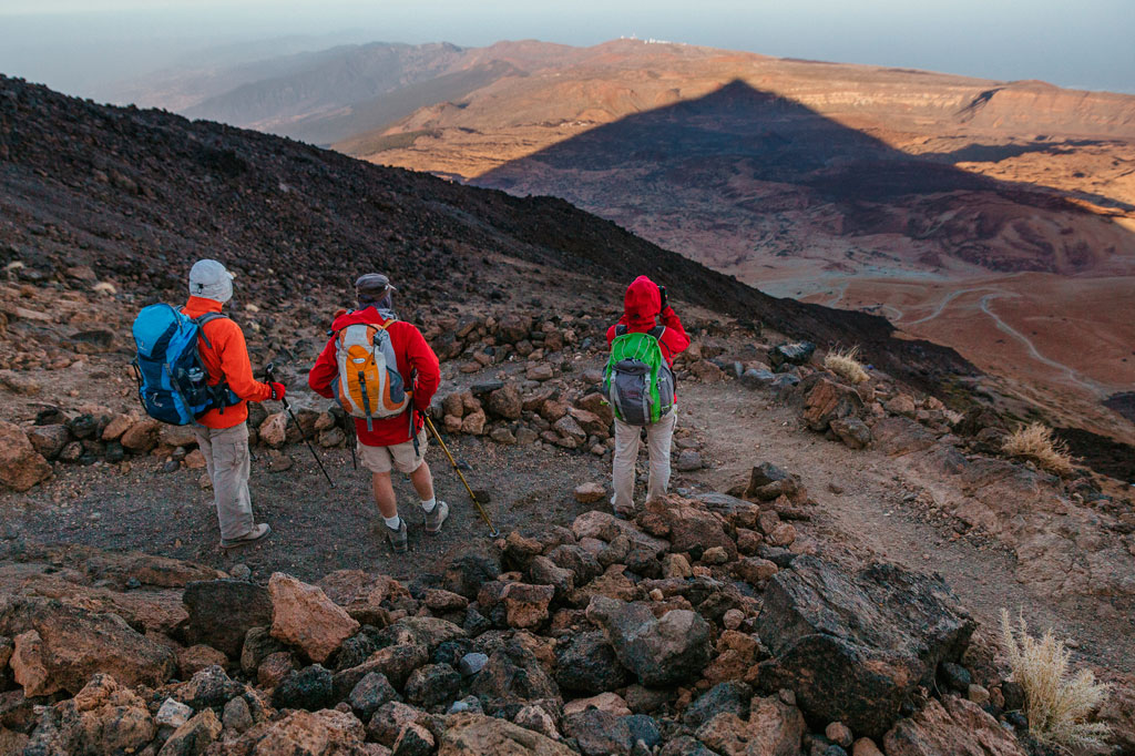 Three hikers hike along rocky trails in Teide National Park, Tenerife.