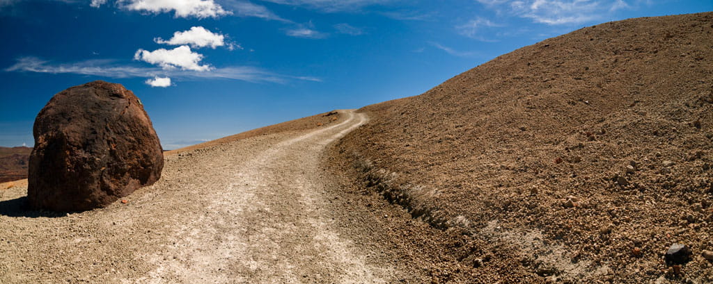 Trail with large rock in arid landscape and blue sky in Tenerife.