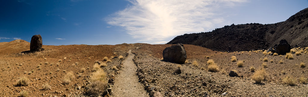 Trail in arid volcanic landscape with large rocks in Teide National Park, Tenerife.