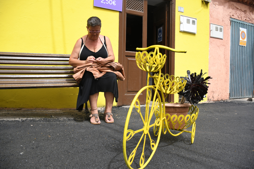Woman sitting on bench next to decorative bicycle in Tenerife.