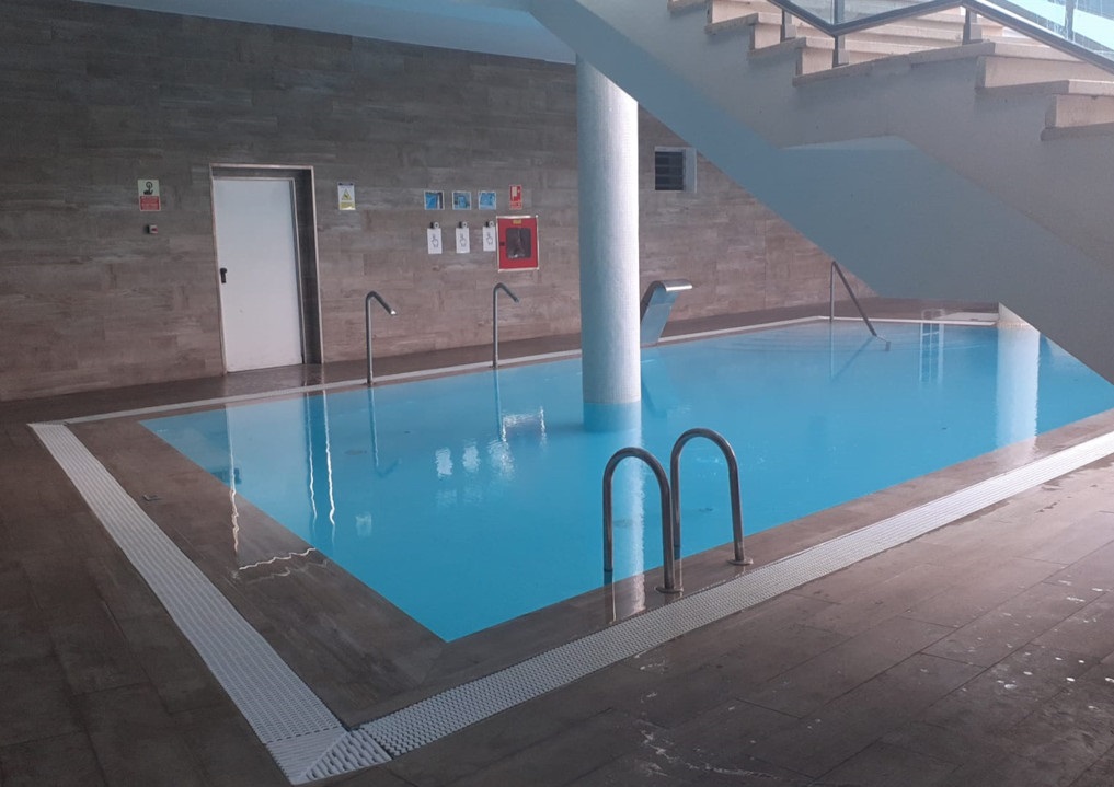 Indoor swimming pool with stairs and signs on the wall in Tenerife.