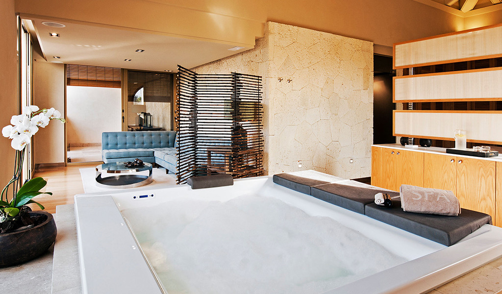 Jacuzzi in spa room with blue sofa and white orchid in Tenerife.