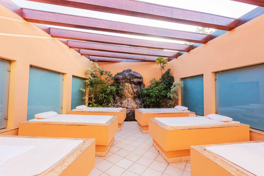 Spa beds in an indoor lounge in Tenerife, surrounded by plants and natural light.