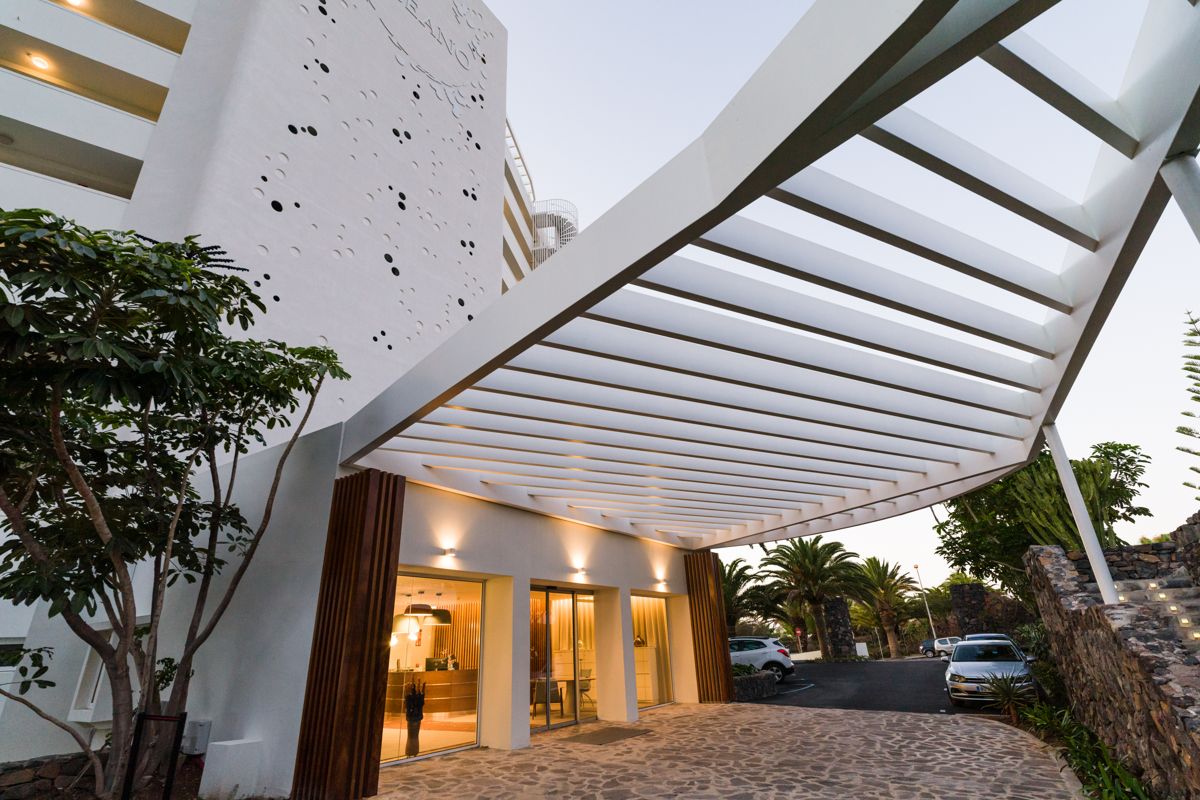 Modern entrance of a hotel in Tenerife with a white roof structure.
