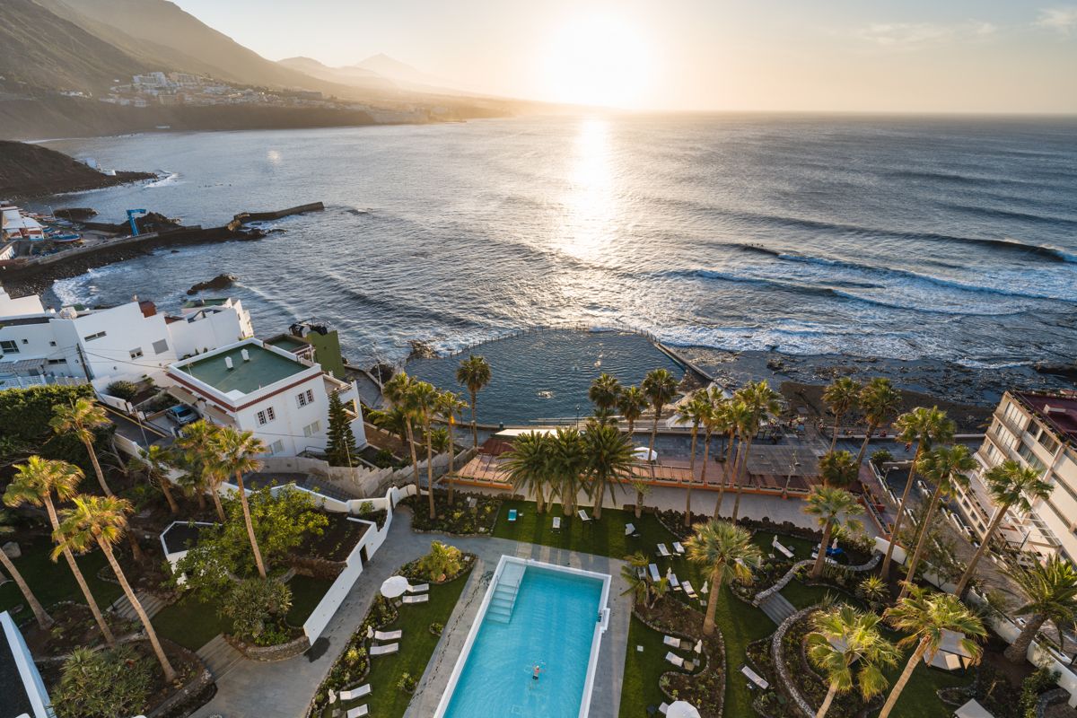 Aerial view of the coast in Tenerife at sunset with pool and gardens.