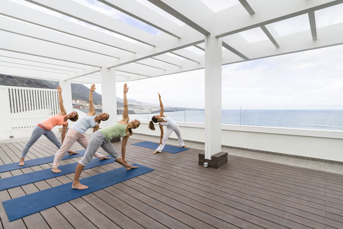 Group practicing yoga outdoors with sea views in Tenerife.