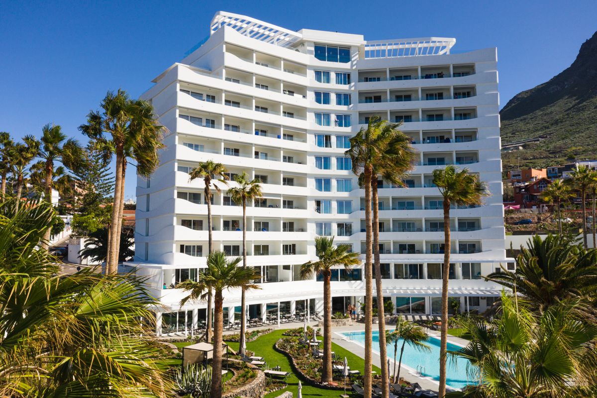 Multi-storey hotel with palm trees and swimming pool in Tenerife.
