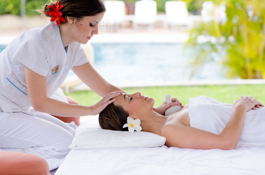 Therapist gives a massage to a woman lying by the pool in Tenerife.
