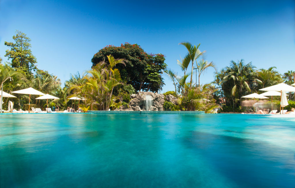 Swimming pool with parasols and tropical vegetation in a hotel in Tenerife.